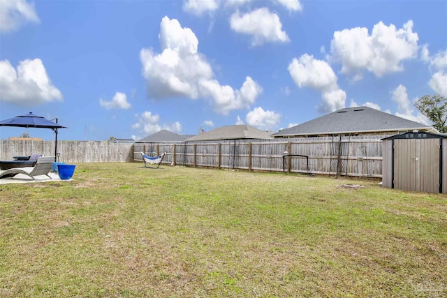 view of yard with a storage shed, an outdoor structure, and a fenced backyard