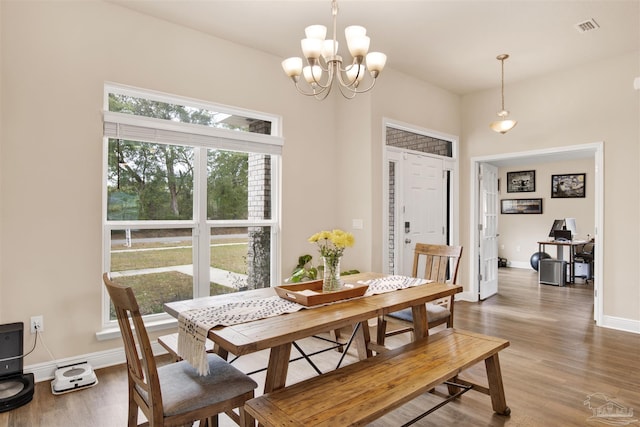 dining space featuring baseboards, wood finished floors, visible vents, and a notable chandelier