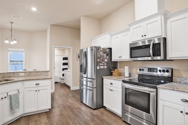 kitchen featuring pendant lighting, visible vents, appliances with stainless steel finishes, white cabinetry, and wood finished floors