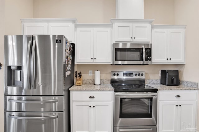 kitchen featuring light stone counters, appliances with stainless steel finishes, and white cabinetry