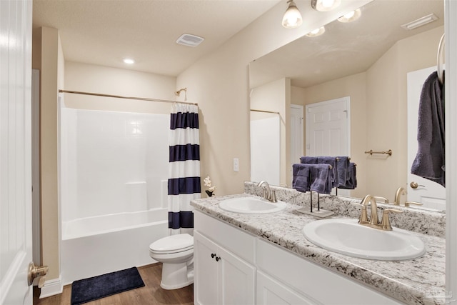 full bath featuring wood finished floors, a sink, toilet, and shower / tub combo