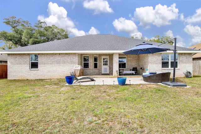 rear view of house with brick siding, a patio area, fence, and a yard