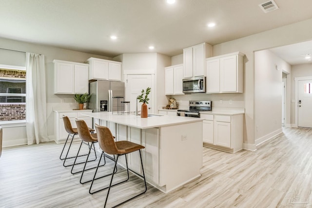 9777 Windy Hill Rd, Pensacola, FL 32526 - kitchen with stainless steel appliances, a breakfast bar, a center island with sink, white cabinetry, and recessed lighting