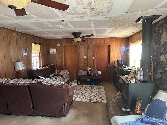 2939 Sundance Ln, Cantonment, FL 32533 - living area with a wood stove, wooden walls, healthy amount of natural light, ceiling fan, and concrete floors