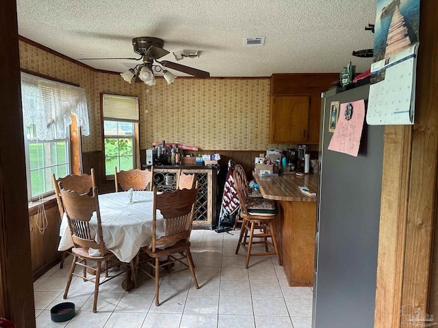 2939 Sundance Ln, Cantonment, FL 32533 - dining room with wallpapered walls, ceiling fan, a textured ceiling, wainscoting, and light tile patterned floors