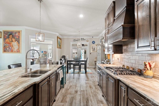 2420 Okatie Ln, Cantonment, FL 32533 - kitchen with a sink, tasteful backsplash, dark brown cabinetry, stainless steel gas stovetop, and custom range hood
