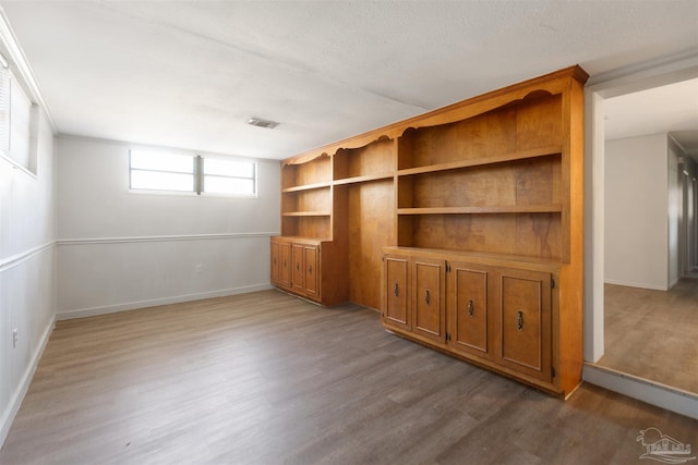 unfurnished living room with built in shelves and hardwood / wood-style floors