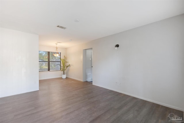 empty room featuring dark hardwood / wood-style flooring and a notable chandelier