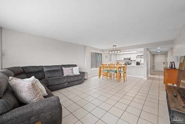 living area featuring light tile patterned flooring, a chandelier, and baseboards
