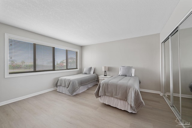 bedroom featuring wood finished floors, a closet, a textured ceiling, and baseboards