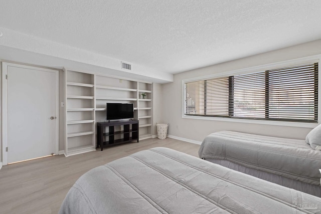 bedroom with a textured ceiling, baseboards, and light wood finished floors