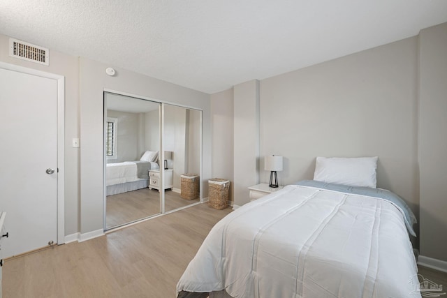 bedroom featuring light wood-type flooring, a closet, and baseboards