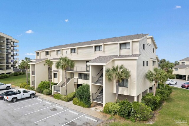 view of property with uncovered parking and stairs