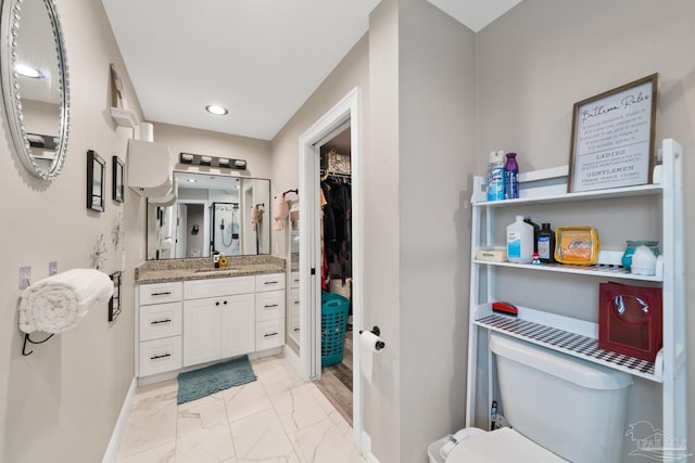 bathroom with vanity, baseboards, a spacious closet, toilet, and marble finish floor