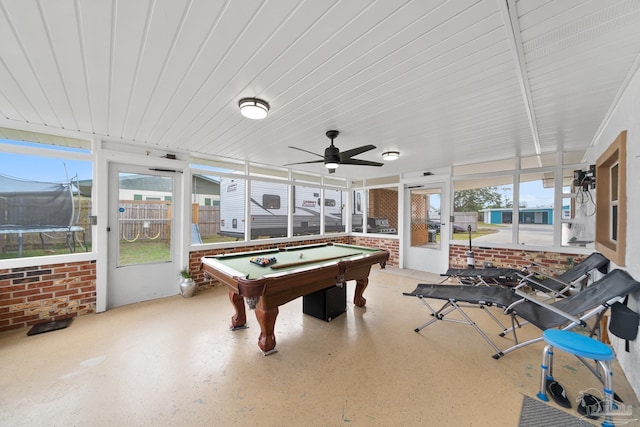 rec room with ceiling fan, speckled floor, and brick wall