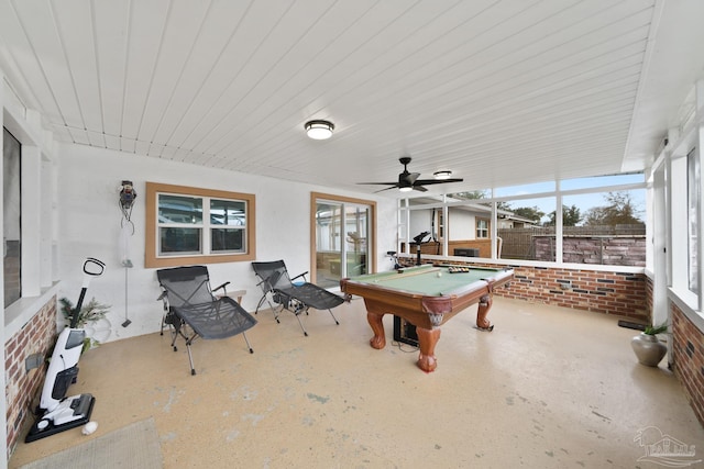 rec room with pool table, a ceiling fan, and brick wall