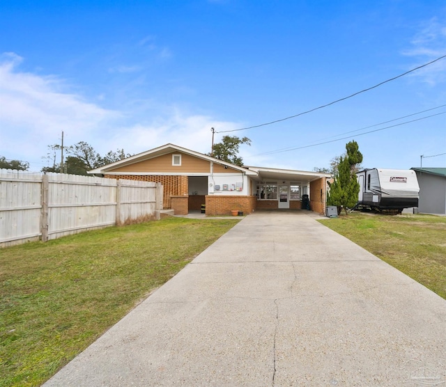 ranch-style home with brick siding, a front lawn, fence, concrete driveway, and a carport