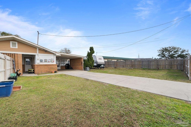 view of yard with a carport, fence private yard, and concrete driveway