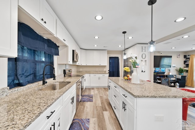 kitchen with light stone countertops, a kitchen island, light wood-style flooring, stainless steel appliances, and a sink