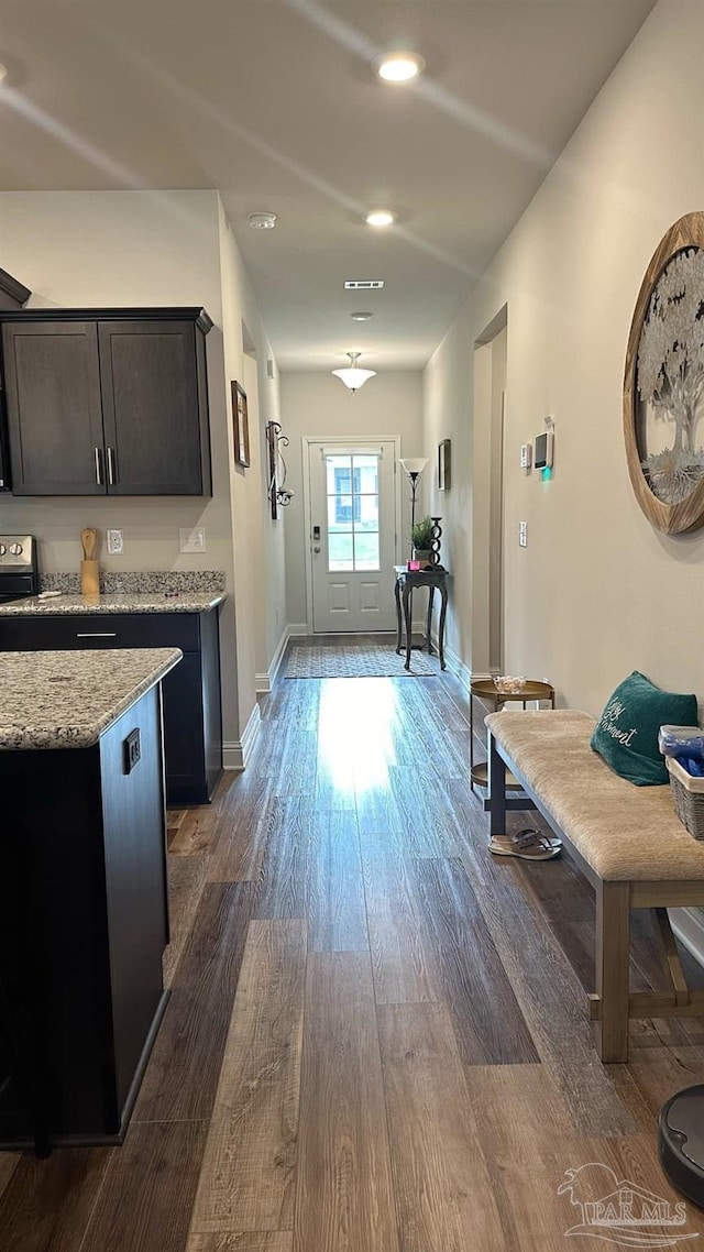 interior space with dark wood-type flooring, light stone countertops, stove, and dark brown cabinetry