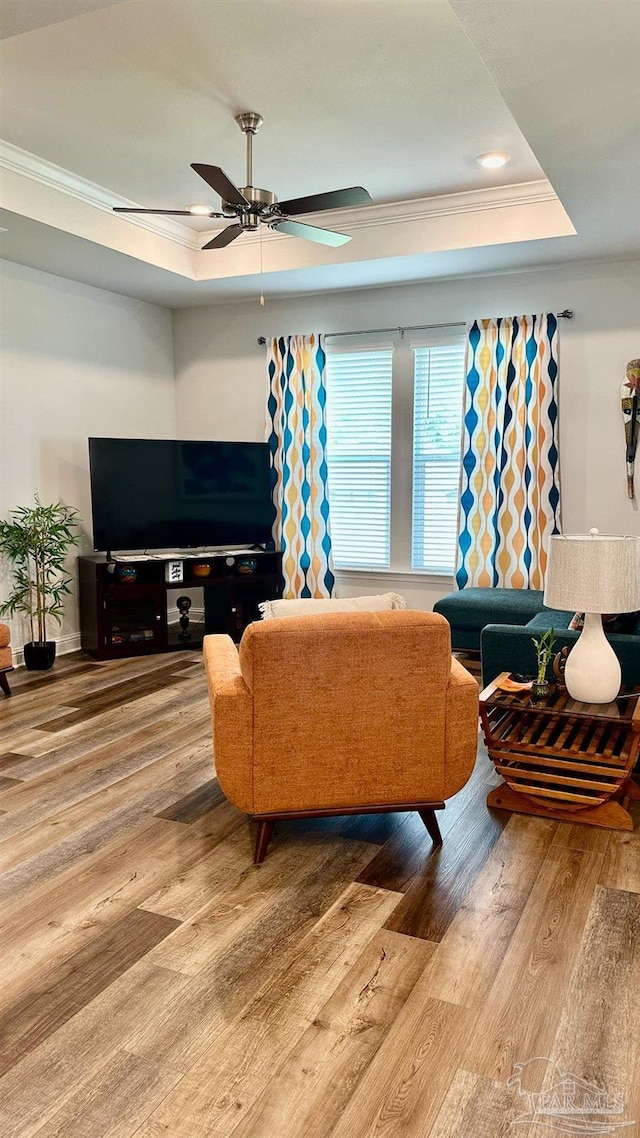 living room with crown molding, a raised ceiling, ceiling fan, and hardwood / wood-style floors