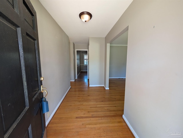 hall with light wood-style flooring and baseboards