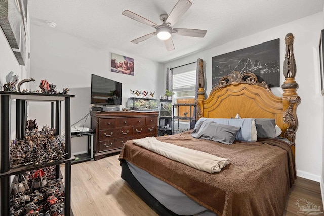 bedroom featuring a ceiling fan, a textured ceiling, baseboards, and wood finished floors