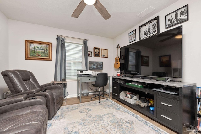 office space featuring a textured ceiling, wood finished floors, visible vents, a ceiling fan, and baseboards