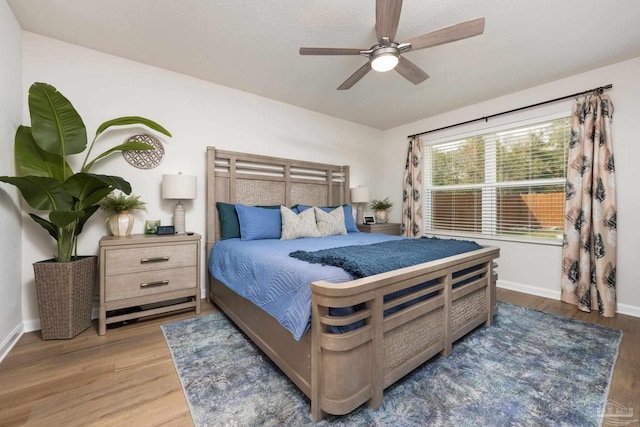 bedroom with a ceiling fan, baseboards, and wood finished floors