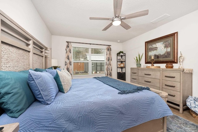 bedroom featuring a textured ceiling, ceiling fan, wood finished floors, and visible vents