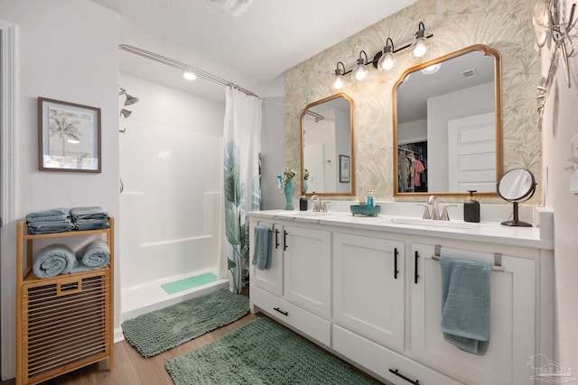 full bath featuring double vanity, curtained shower, a sink, and wood finished floors