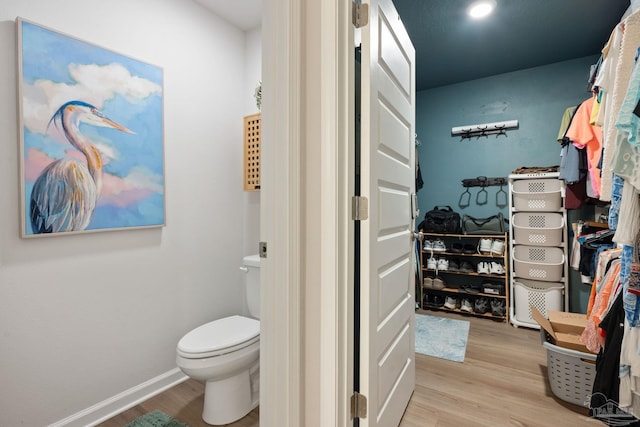 bathroom with toilet, baseboards, and wood finished floors