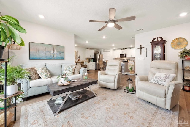 living room featuring light wood-style flooring, visible vents, ceiling fan, and recessed lighting