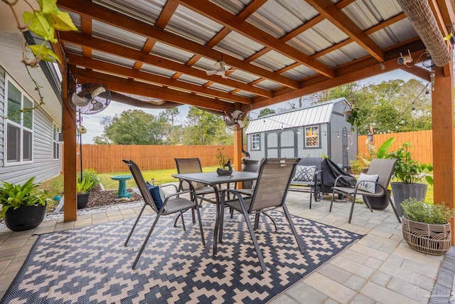 view of patio / terrace featuring ceiling fan, outdoor dining area, an outdoor structure, and a fenced backyard