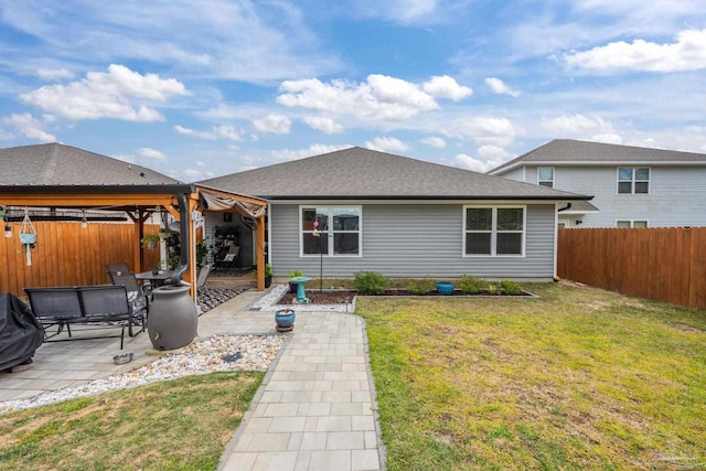 back of house with a shingled roof, a lawn, a fenced backyard, a gazebo, and a patio area