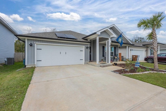 single story home with a garage, concrete driveway, roof mounted solar panels, a front lawn, and board and batten siding