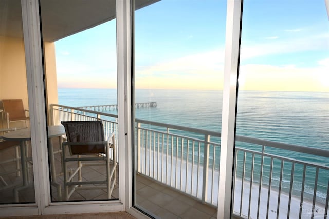 balcony at dusk with a water view and a beach view