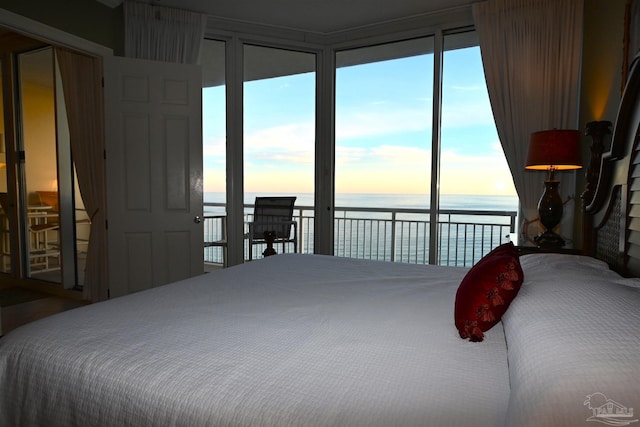 bedroom with access to outside, multiple windows, and a water view