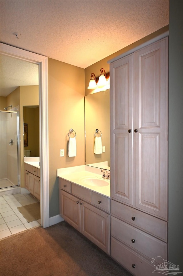 bathroom featuring a textured ceiling, vanity, tile patterned floors, and a shower with shower door