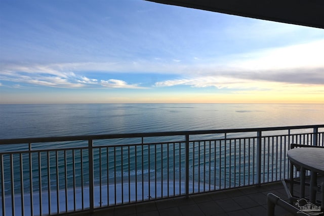 balcony at dusk featuring a water view