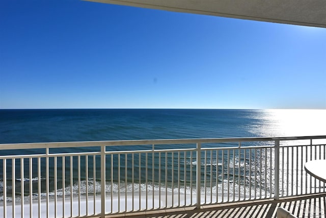 balcony with a water view and a view of the beach