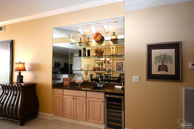 bar with dark stone counters, beverage cooler, crown molding, sink, and light tile patterned floors