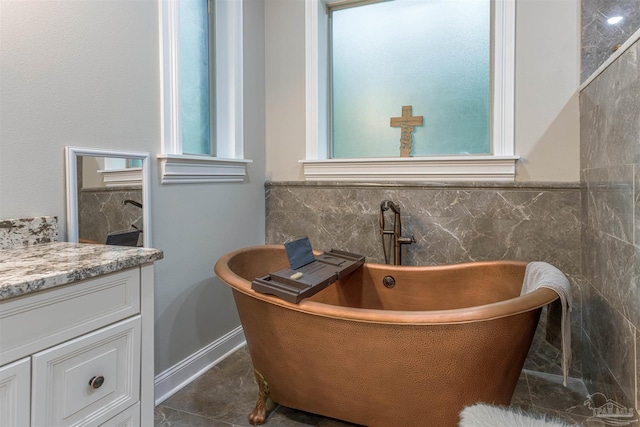 bathroom featuring vanity, a bathing tub, tile patterned flooring, and tile walls