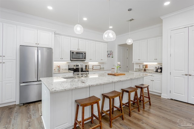 kitchen featuring crown molding, appliances with stainless steel finishes, light hardwood / wood-style flooring, and a kitchen island with sink