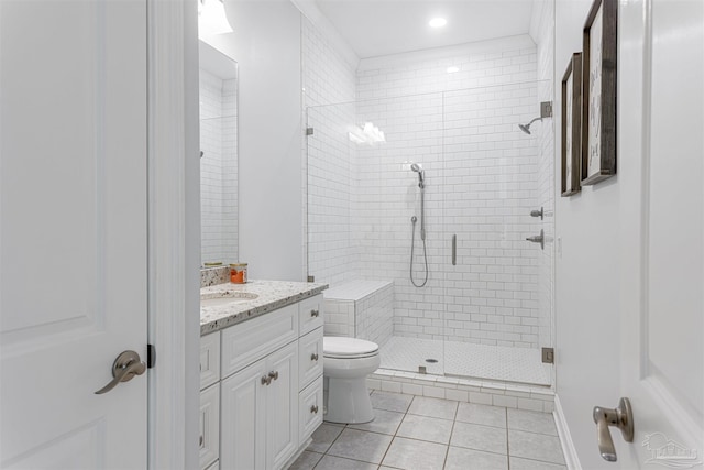 bathroom with a shower with door, vanity, tile patterned flooring, and toilet