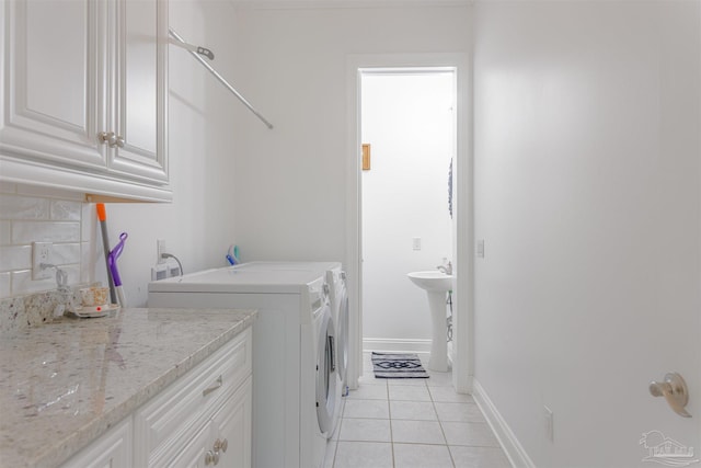 clothes washing area featuring cabinets, separate washer and dryer, and light tile patterned floors