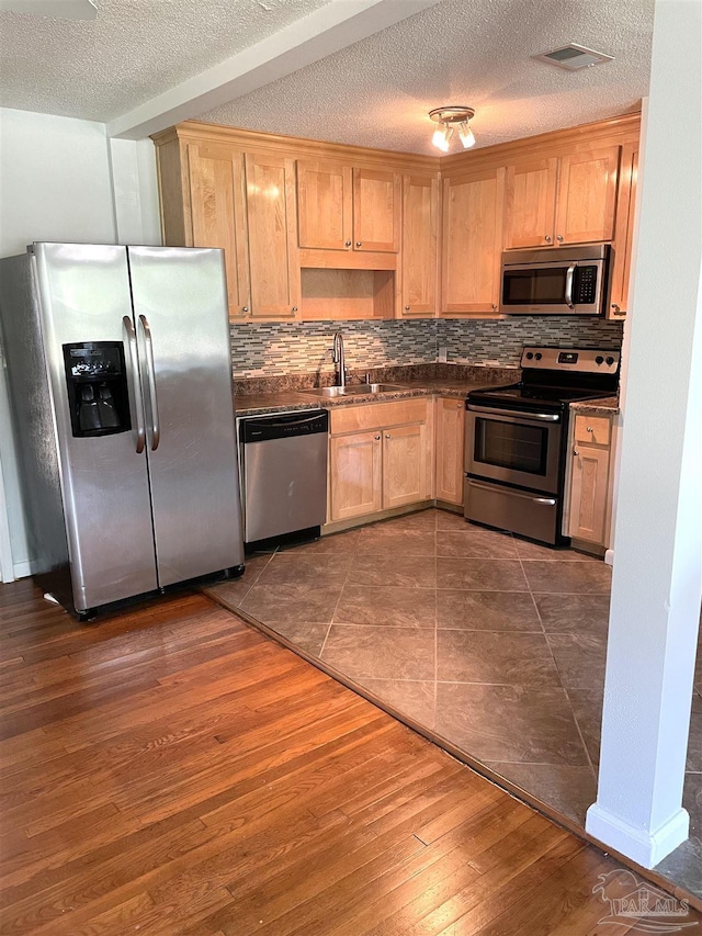 kitchen featuring appliances with stainless steel finishes, backsplash, a textured ceiling, sink, and dark hardwood / wood-style floors