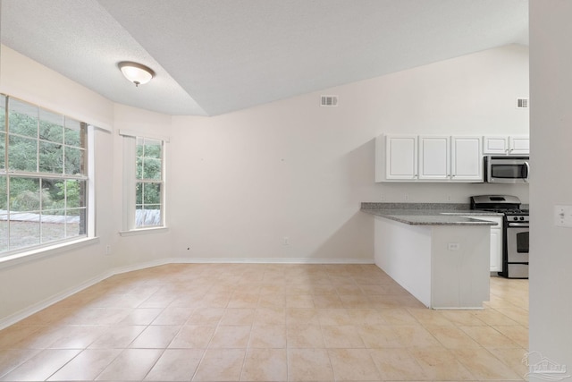 kitchen with white cabinetry, kitchen peninsula, vaulted ceiling, light tile patterned floors, and appliances with stainless steel finishes