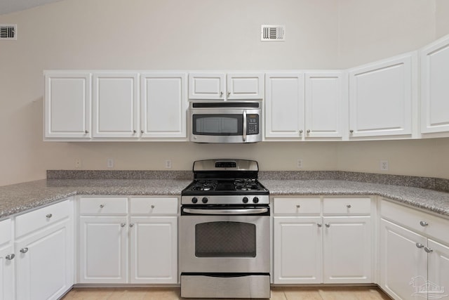 kitchen with white cabinetry, appliances with stainless steel finishes, and vaulted ceiling