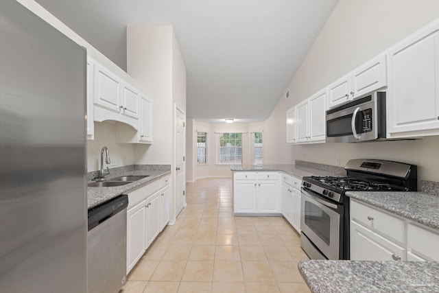 kitchen with sink, white cabinetry, stainless steel appliances, and vaulted ceiling